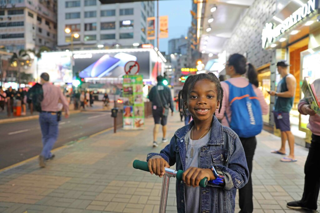 black kids travel, black boy riding scooter in hong kong