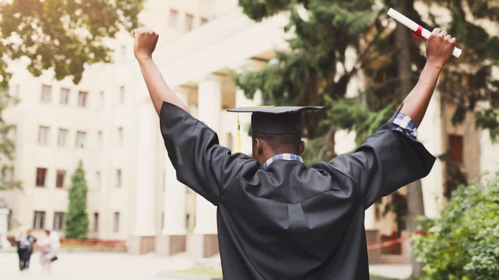 a young man with his arms raised in the air in celebration after graduating in college