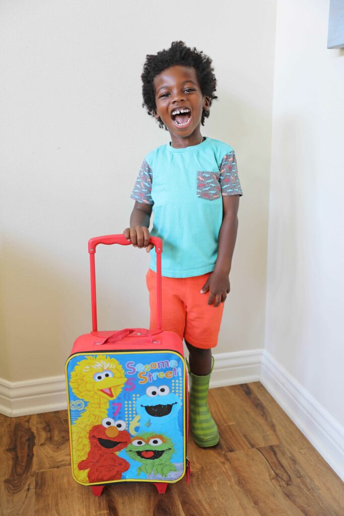 A kid with a sesame street suitcase