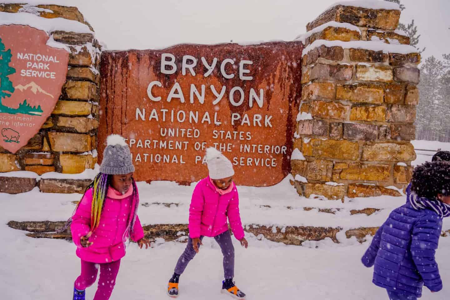 Children playing in front of the Bryce Canyon National Park sign.