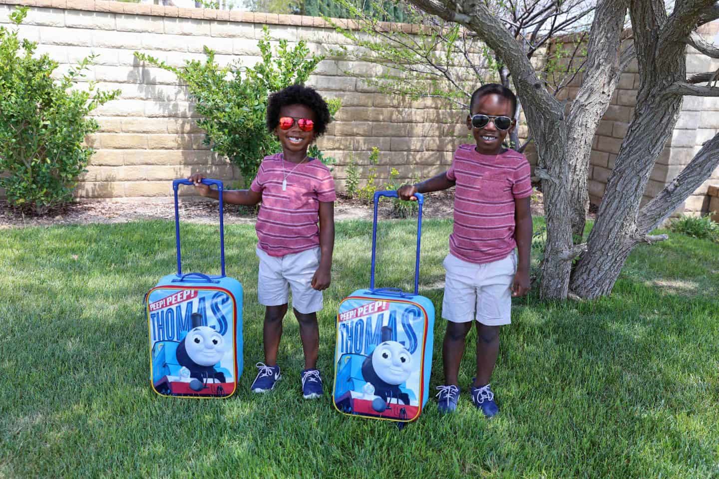 two children in sunglasses with Thomas the Train suitcases - how to vacation in palm springs with kids